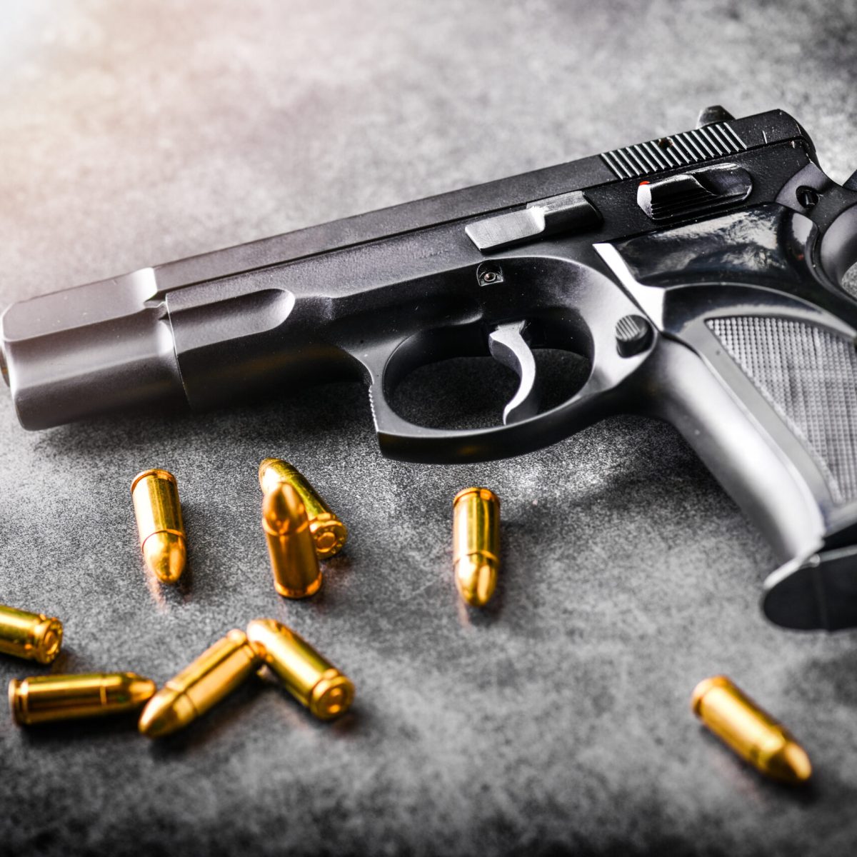 Hand,Gun,With,Ammunition,On,Dark,Stone,Background.,9,Mm